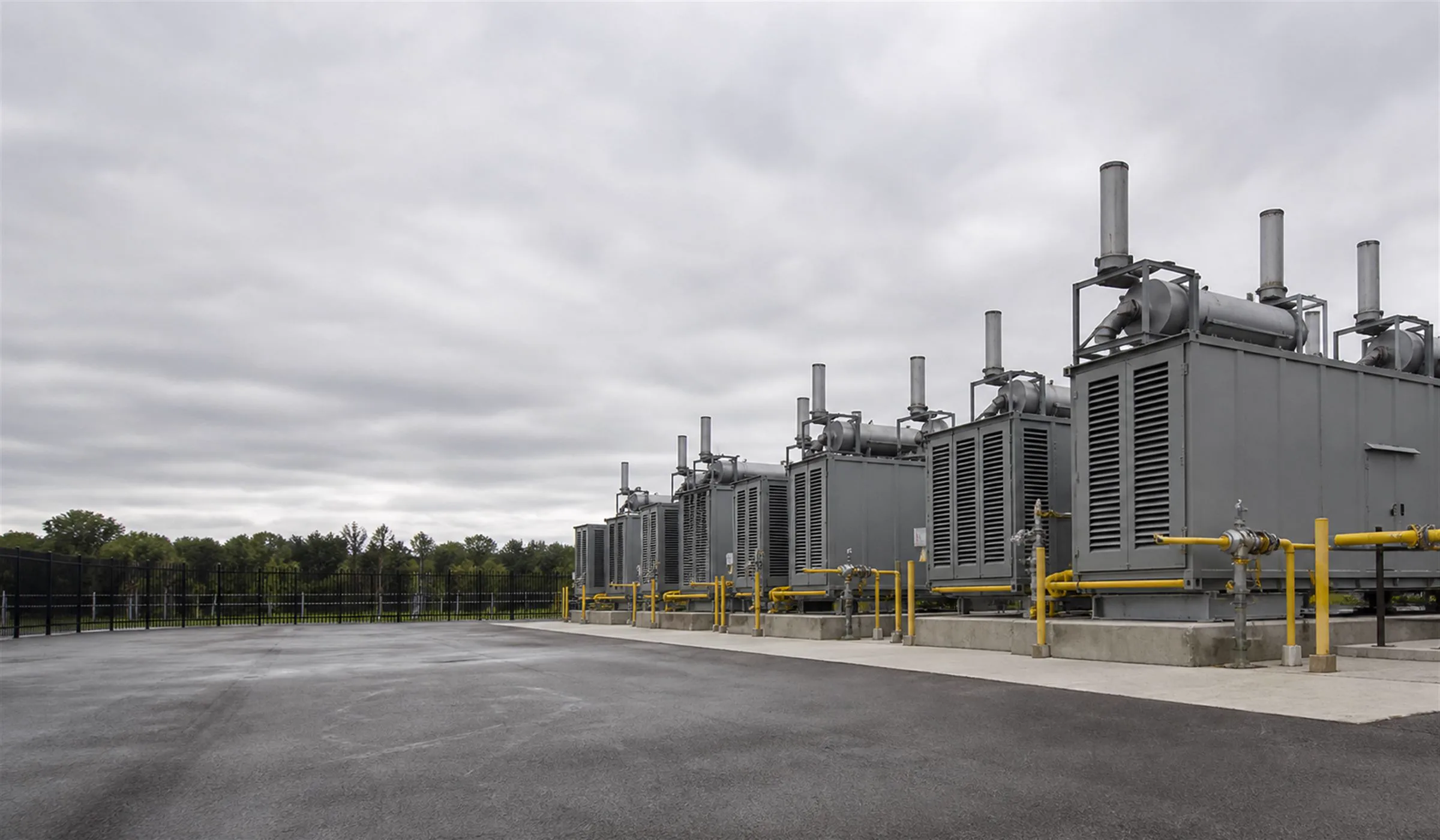 Row of modular gas generator enclosures in a fenced utility yard